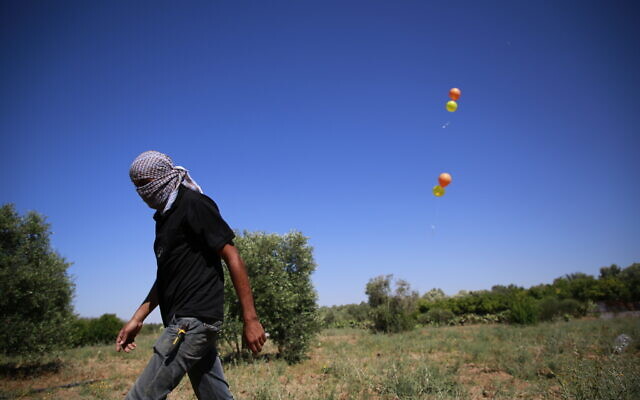 Masked Palestinian members of the Islamic Jihad terror group launch incendiary balloons from Gaza toward Israel on June 15, 2021. (Atia Mohammed/FLASH90)