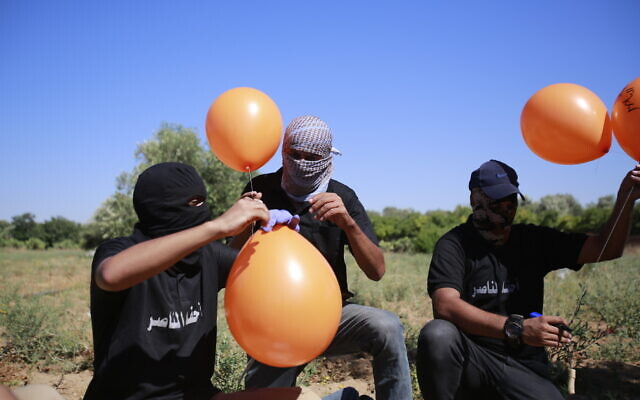Supporters of the Palestinian Islamic Jihad terror group prepare balloon-borne incendiary devices to launch toward Israel, east of Gaza City, on June 15, 2021. (Atia Mohammed/Flash90)