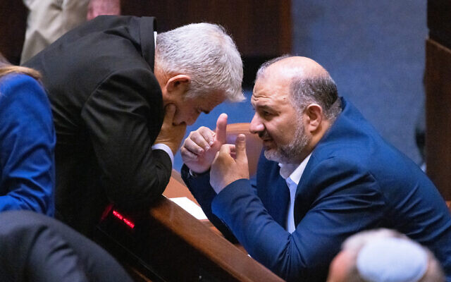 Foreign Minister Yair Lapid (L) speaks with MK Mansour Abbas, head of the Islamist Ra'am party, in the Knesset plenum on June 21, 2021. (Olivier Fitoussi/Flash90)