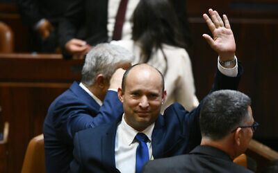 Newly elected Prime Minister Naftali Bennett waves, with Yair Lapid (left) and Gideon Sa'ar (right) alongside him, after their new coalition wins Knesset approval, June 13, 2021 (Haim Zach / GPO)