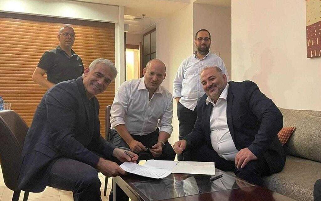 Yesh Atid leader Yair Lapid (L), Yamina leader Naftali Bennett (C) and Ra'am leader Mansour Abbas sign a coalition agreement on June 2, 2021. (Courtesy of Ra'am)