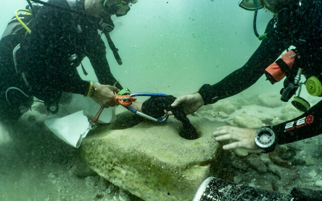 In this handout photo from June 10, 2021, scuba divers with an ancient stone anchor that was found at the Tel Dor archaeological site in northern Israel. (Amir Yurman of the University of Haifa's Maritime Workshop)