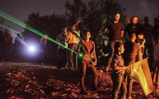 Palestinian protesters use laser torches during a demonstration against the Israeli settlers' outpost of Evyatarin the West Bankon July 1, 2021.  (Photo by JAAFAR ASHTIYEH / AFP)