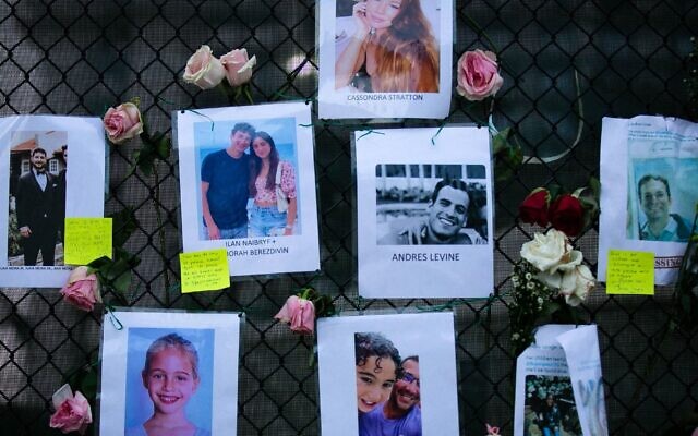 Images of Andres Levine, Ilan Naibryf and Deborah Berezdivin, three of the Jewish victims of the Surfside building collapse, in center among other photographs of those missing posted at a makeshift memorial on the building site in Surfside, Fla., June 26, 2021. (Andrea Sarcos/AFP)