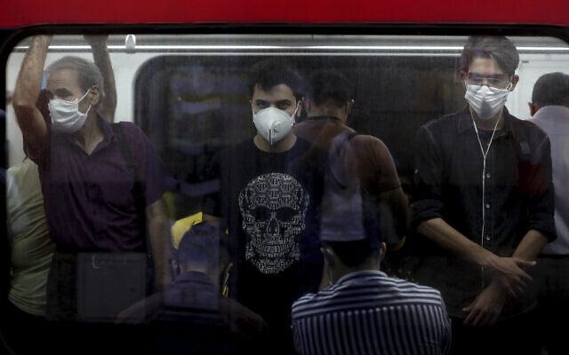 Illustrative: People wearing protective face masks to help prevent the spread of the coronavirus stand inside a train in Tehran, Iran on July 8, 2020. (AP/Ebrahim Noroozi)