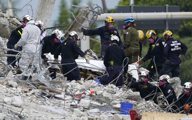 In this Monday, July 5, 2021, file photo, rescue workers move a stretcher containing recovered remains at the site of the collapsed Champlain Towers South condo building, in Surfside, Florida. (AP/Lynne Sladky)