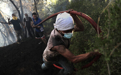 Civil defense workers extinguish a forest fire, at Qobayat village, in the northern Akkar province, Lebanon, on Thursday, July 29, 2021. (AP Photo/Hussein Malla)