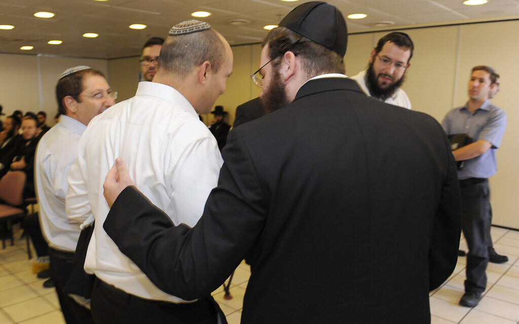An ultra-Orthodox Jewish man speaks with then-Economy Minister Naftali Bennett following a discussion about drafting ultra-Orthodox men to service in the Israeli army in the Yad Sara building in Jerusalem, on June 11, 2013. (Zuzana Janku/Flash 90)
