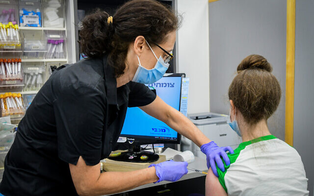 An Israeli teenager receives a COVID-19 vaccine at a Maccabi clinic in Tel Aviv, June 22, 2021. (Avshalom Sassoni/Flash90)
