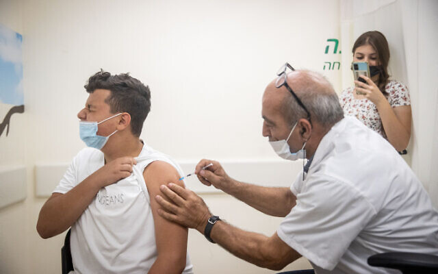 An Israeli teen receives a coronavirus vaccination in Jerusalem on June 24, 2021. (Yonatan Sindel/Flash90)