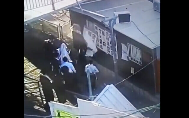 A screenshot of security camera footage shows suspects vandalizing posters of the victims of the Mount Meron disaster. (Screen capture: Twitter)