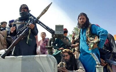 Taliban fighters sit over a vehicle on a street in Laghman province on August 15, 2021. (AFP)