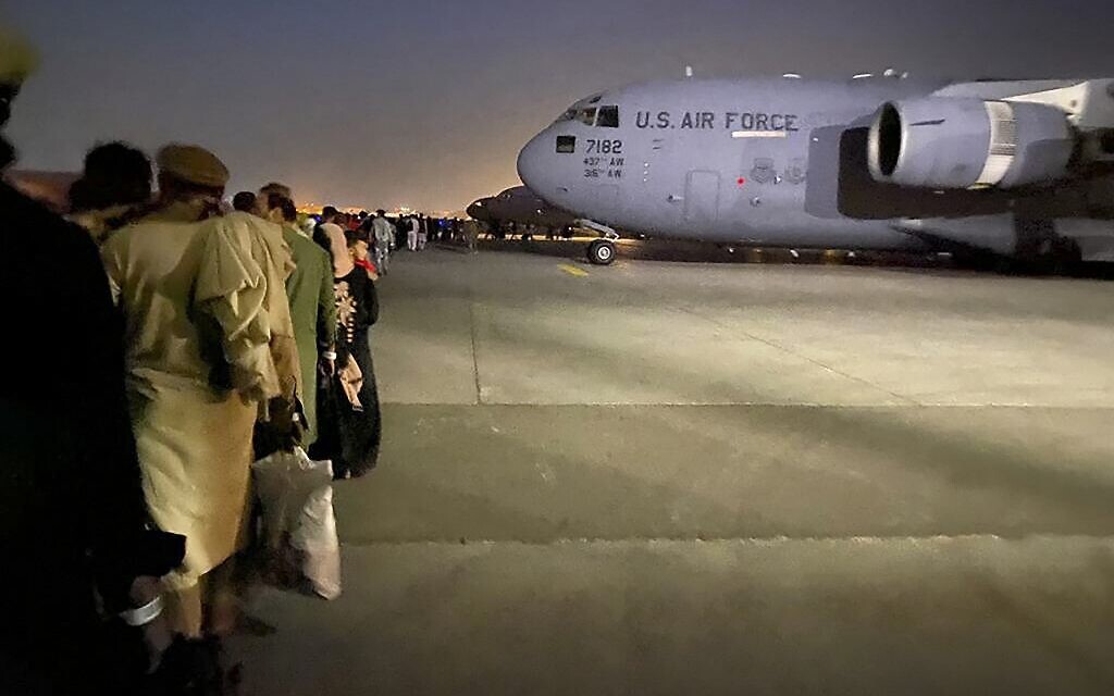 Afghan people queue up and board a US military aircraft to leave Afghanistan, at the military airport in Kabul on August 19, 2021 after Taliban's military takeover of Afghanistan. (Shakib RAHMANI / AFP)