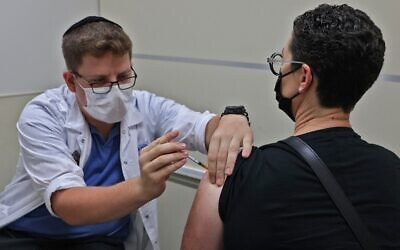 A health worker administers a third dose of the Pfizer-BioNtech COVID-19 vaccine at a Maccabi Health Services clinic in Jerusalem, on August 20, 2021, soon after Israel approved booster shots for people over 40 - a decision that was later expanded to. the entire population. (Ahmad Gharabli/AFP)