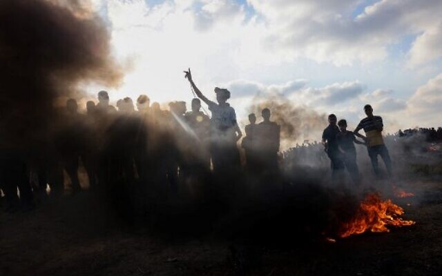 Palestinians stand by burning tires during a demonstration by the border fence with Israel, east of Gaza City on August 21, 2021. (Photo by SAID KHATIB / AFP)