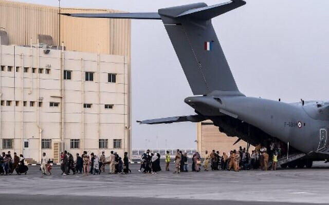 File: People walk on the tarmac as they disembark from a Airbus A400M military transport aircraft at the French military air base near Abu Dhabi, on August 23, 2021, after being evacuated from Kabul. (Bertrand Guay/AFP)