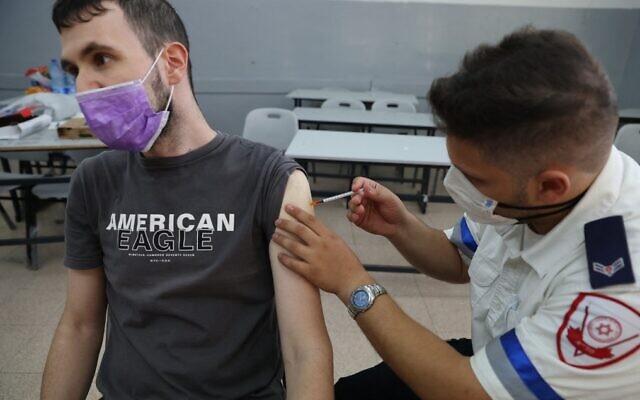 A Magen David Adom paramedic administers a third dose of the Pfizer-BioNTech COVID-19 vaccine to an Israeli man, on August 24, 2021, in the Tel Aviv suburb of Holon. (Ahmad Gharabli/AFP)
