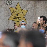 In this July 24, 2021, file photo, people stage a protest against the 'green pass' in Milan, Italy. Protesters in Italy and in France have been wearing yellow Stars of David, like the ones Nazis required Jews to wear to identify themselves during the Holocaust. Some carry signs likening vaccine passes to  dictatorships. (AP Photo/Antonio Calanni, File)