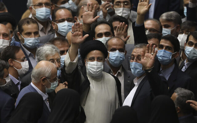 President Ebrahim Raisi, center, waves to journalists as he is surrounded by group of lawmakers after taking his oath as president at the parliament in Tehran, Iran, on Thursday, August 5, 2021. (AP Photo/Vahid Salemi)