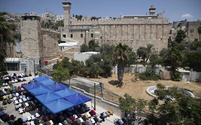 Palestinians pray during Friday prayers at a protest against the construction of disabled access being built at the Tomb of the Patriarchs, in the West Bank city of Hebron, on August 13, 2021. (AP/Majdi Mohammed)