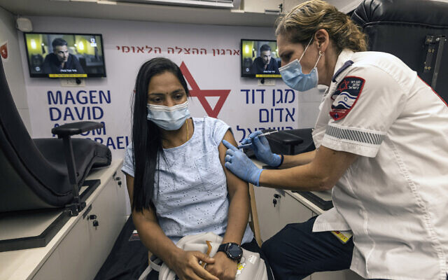 A medic from Israel's Magen David Adom emergency service administers a booster shot of the coronavirus vaccine to a woman in Tel Aviv, Israel, Aug. 14, 2021 (AP Photo/Tsafrir Abayov)