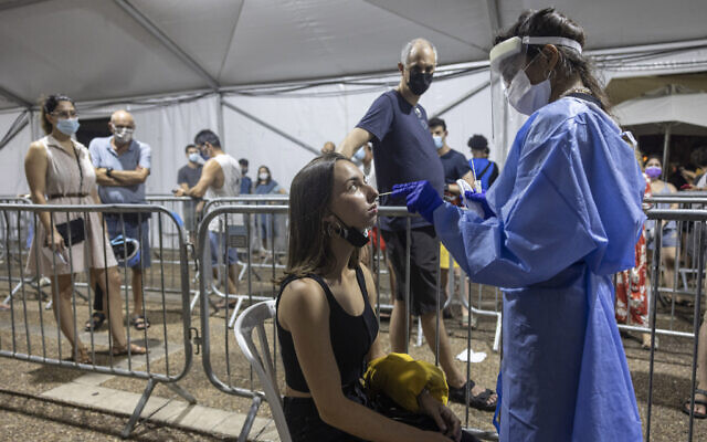 A medical professional takes samples from a woman for a coronavirus test in Rabin Square in Tel Aviv on Aug. 14, 2021. (AP Photo/Tsafrir Abayov)