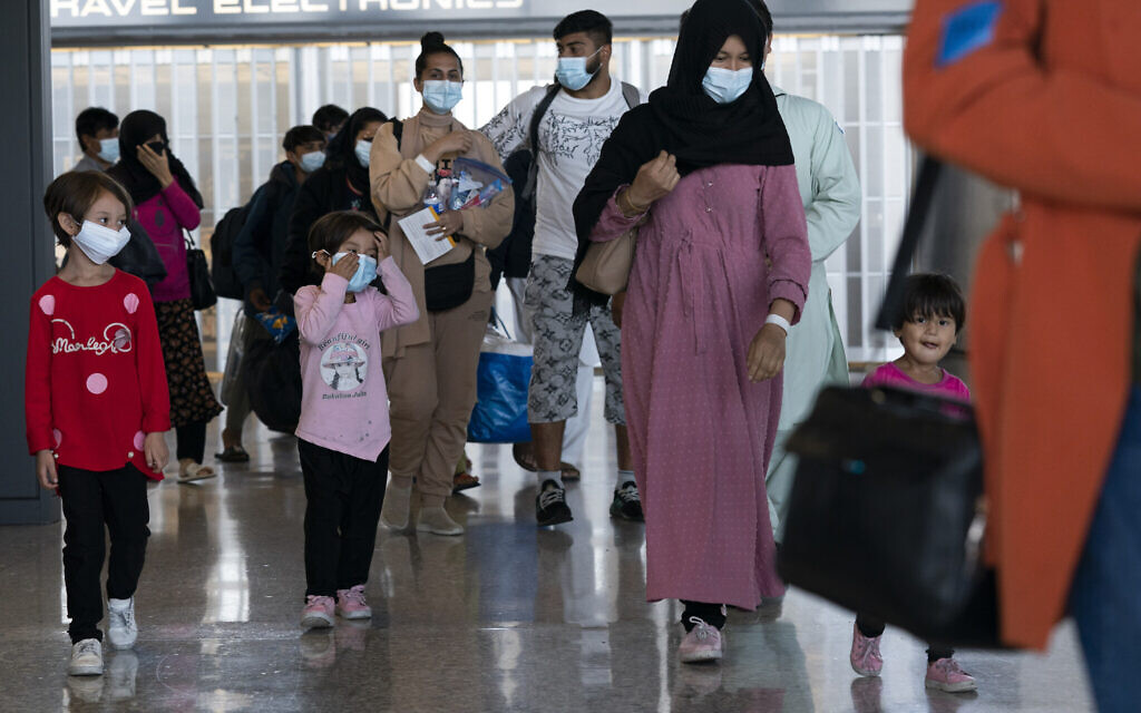 Families evacuated from Kabul, Afghanistan, walk through the terminal before boarding a bus after they arrived at Washington Dulles International Airport, in Chantilly, Va., on Wednesday, Aug. 25, 2021. (AP Photo/Jose Luis Magana)