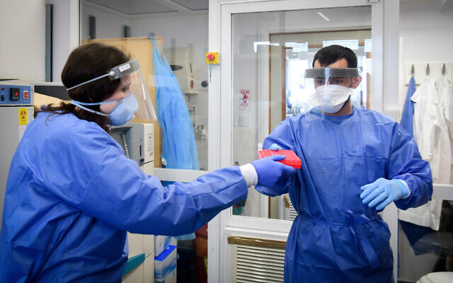 Medical staff at the Barzilai hospital, in the southern Israeli city of Ashkelon, wear protective gear, as they handle a coronavirus test sample on March 29, 2020. (Flash90)