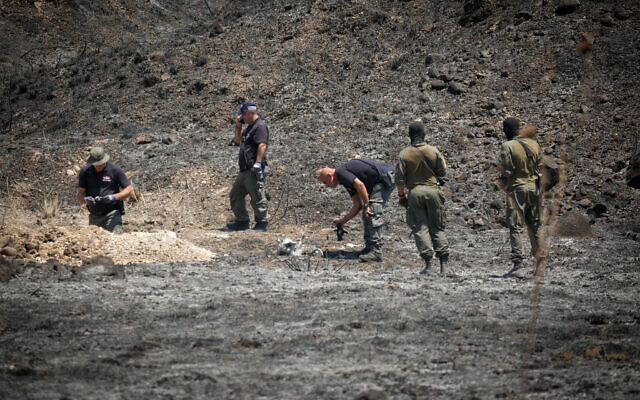 Israeli security forces at the scene where a rocket landed near the city of Kiryat Shmona, August 4, 2021 (David Cohen/FLASH90)
