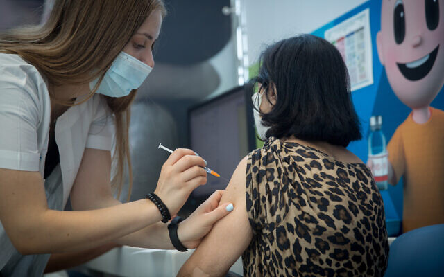 An Israeli woman receives a COVID-19 vaccine booster shot at a Clalit clinic in Tel Aviv on August 10, 2021. (Miriam Alster/Flash90 )