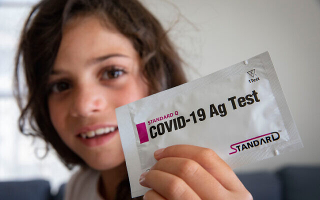 A child poses with her COVID-19 home kit test that she received from her school, ahead of the opening of the new school year, in Jerusalem, on August 30, 2021. (Olivier Fitoussi/Flash90)