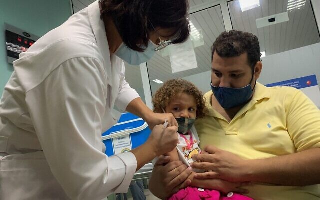 Pedro Montano holds his daughter Roxana Montano, 3, while she is being vaccinated against COVID-19 with Cuban vaccine Soberana Plus, on August 24, 2021 at Juan Manuel Marquez hospital in Havana, as part of a vaccine study in children and adolescents. (ADALBERTO ROQUE / AFP)