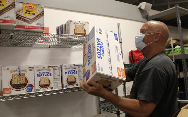 Volunteer Marty Heiman loads Passover matzos onto a shelf at the Jewish Community Services Kosher Food Bank during the new coronavirus pandemic, Wednesday, April 8, 2020, in North Miami Beach, Fla. (AP Photo/Lynne Sladky)