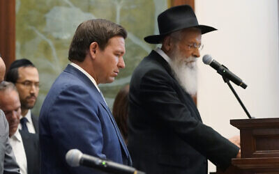 Florida Gov. Ron DeSantis, left, and Rabbi Sholom Lipskar participate in a moment of silence, June 14, 2021, at The Shul of Bal Harbour, Florida. (AP Photo/Wilfredo Lee)