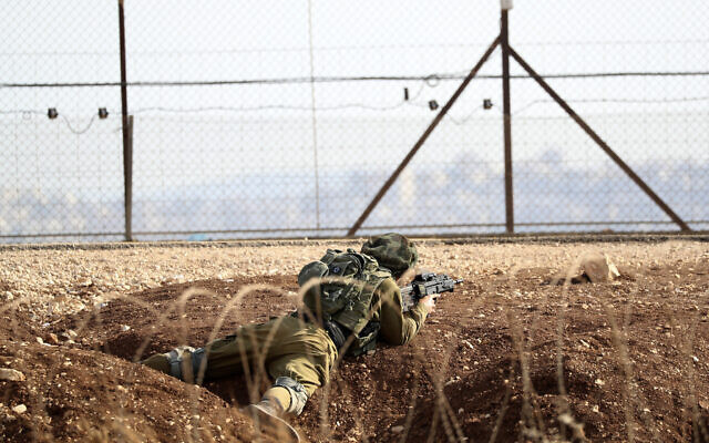 An Israeli soldier takes position along the border between the northern West Bank near Jenin and Israel as they search for two Palestinians who broke out of a maximum-security prison last week, on a road leading to the West Bank town of Jenin, near Gan Ner Israel, September 12, 2021. (Ariel Schalit/AP)
