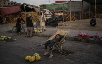 An Afghan boy sits on a wheelbarrow as he waits for customers at a street fruit and vegetable market in Kabul, Afghanistan, September 22, 2021. (AP Photo/Bernat Armangue)