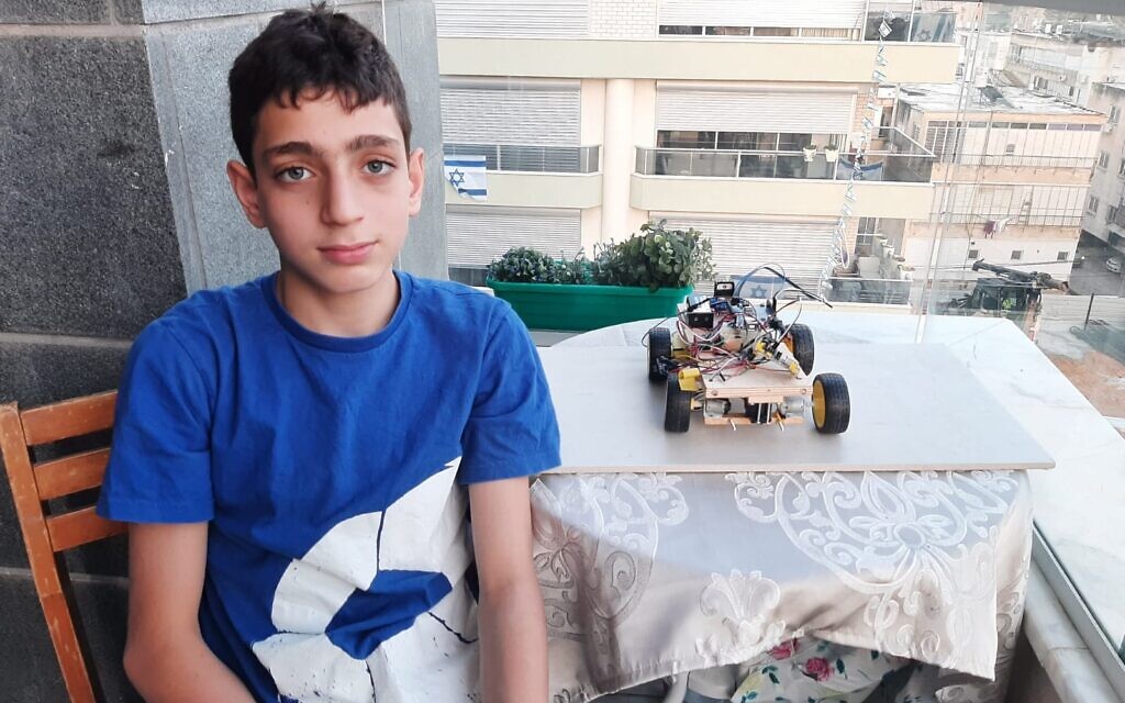 Barak Houry, 12, sits next to a small-scale model of a fire-fighting robot concept he built on his own. Houry was killed while riding his bike on Yom Kippur on September 15, 2021. (Courtesy of the Houry family)