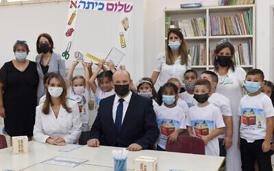 Prime Minister Naftali Bennett and Education Minister Dr. Yifat Shasha-Biton sit with children at the Eli Cohen Meuhad School in Yeruham, at the start of the new school year, on September 1, 2021. (Haim Zach / GPO)
