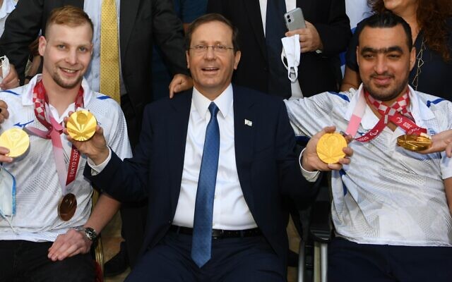 President Isaac Herzog poses for a photo with Paralympic medal winners Mark Malyar (left) and Iyad Shalabi (right) at the president's residence in Jerusalem, on September 14, 2021. (Amos Ben Gershom/GPO)