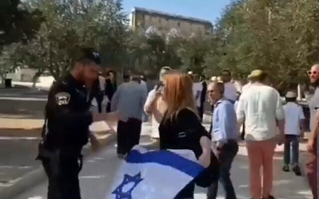 A police officer confiscates an Israeli flag from a woman on the Temple Mount, September 27. 2021. (Video screenshot)
