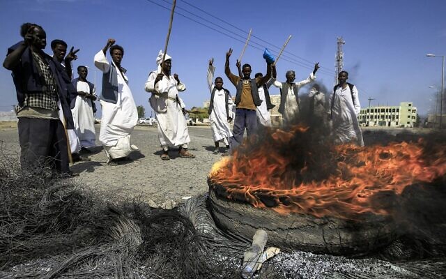 Members of the Beja ethnic group of eastern Sudan gather around burning tires as they demonstrate outside the Osman Digna port in Sudan's northeastern Red Sea coastal city of Suakin on October 9, 2021 (ASHRAF SHAZLY / AFP)