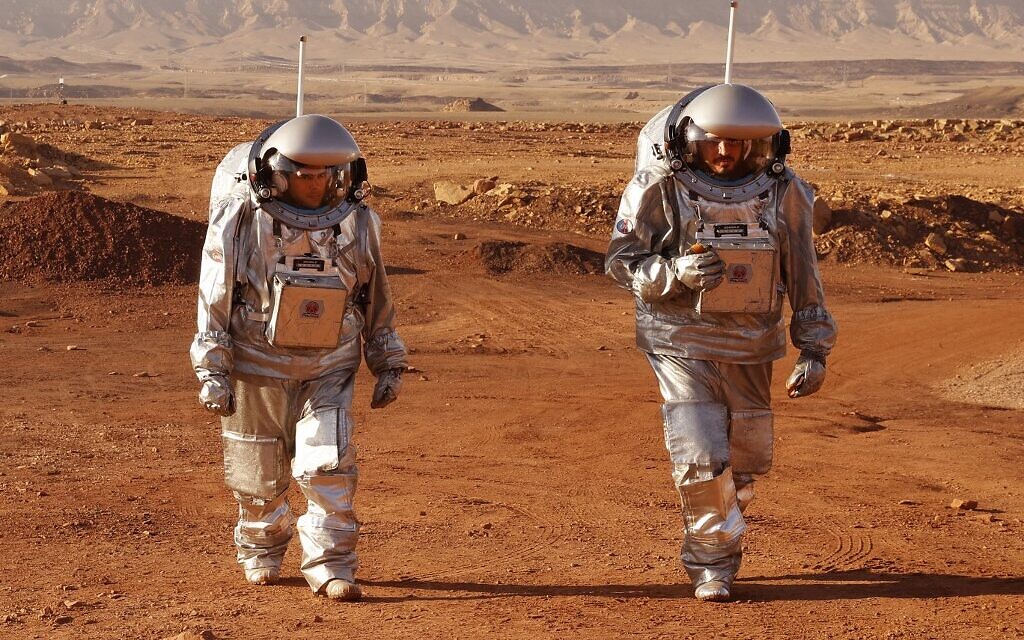 A couple of astronauts from a team from Europe and Israel walk in spacesuits during a training mission for planet Mars at a site that simulates an off-site station at the Ramon Crater in Mitzpe Ramon in Israel's southern Negev desert on October 10, 2021. (Photo by JACK GUEZ / AFP)