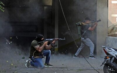 Shiite fighters from Hezbollah and Amal terror movements take aim with (L to R) a Kalashnikov assault rifle and a rocket-propelled grenade launcher amidst clashes in the area of Tayouneh, in the southern suburb of the capital Beirut, on October 14, 2021 (IBRAHIM AMRO / AFP)