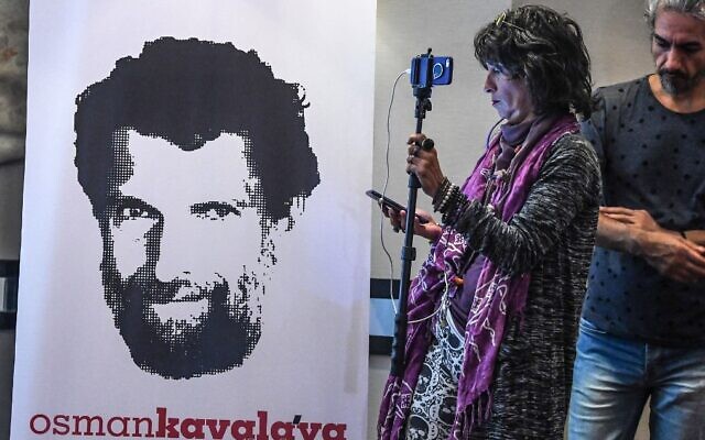 A journalist stands in front of a poster featuring an image of jailed businessman and philanthropist Osman Kavala, during a press conference held by his lawyers in Istanbul, on October 31, 2018. (Ozan Kose/AFP/File)