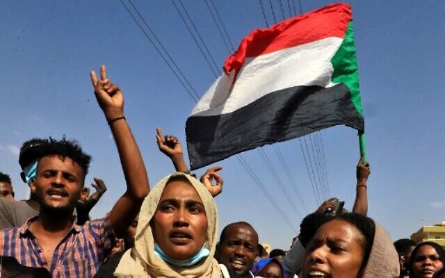 Sudanese protesters flash victory signs and lift national flags as they demonstrate on 60th Street in the capital Khartoum, to denounce overnight detentions by the army of government members, on October 25, 2021. (Photo by AFP)