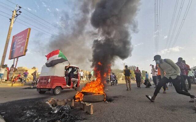 Sudanese anti-coup protesters wave the national flag as they gather in a street in the capital Khartoum, on October 30, 2021, to express their support for the country's democratic transition which a military takeover and deadly crackdown derailed. (AFP)