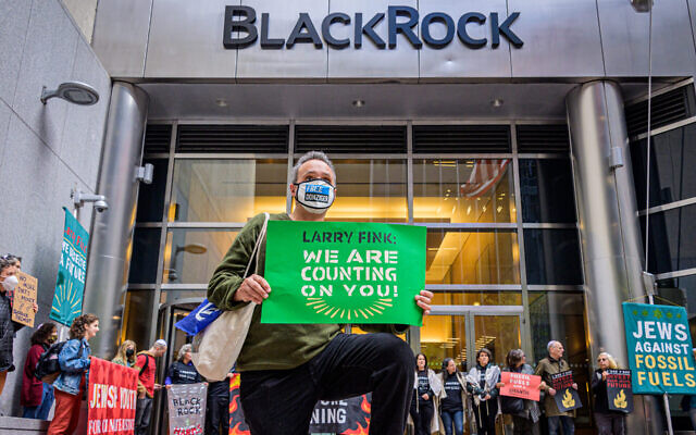 A demonstrator kneels in front of the headquarters of BlackRock in Manhattan, demanding the investment firm's CEO Larry Fink defund the fossil fuel industry, October 18, 2021. (courtesy, Erik McGregor via JTA)