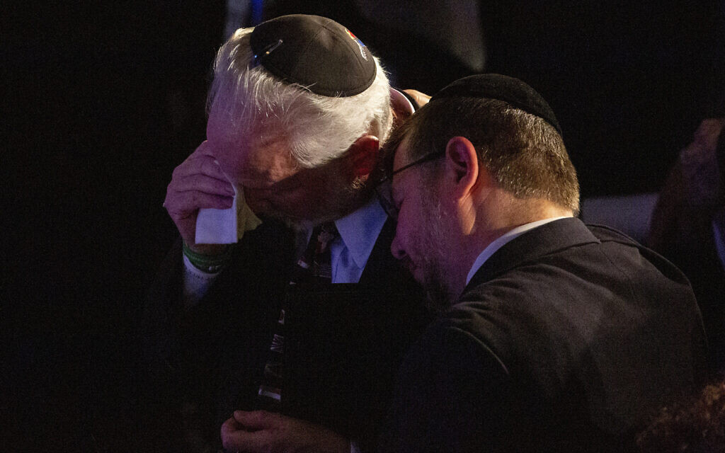 Rabbi Jeffrey Myers, center, of the Tree of Life/Or L'Simcha Congregation, is comforted after saying a prayer for the souls of the deceased during the one-year commemoration of the Tree of Life synagogue attack, at Soldiers & Sailors Memorial Hall and Museum,  October 27, 2019, in Pittsburgh. (AP Photo/Rebecca Droke)
