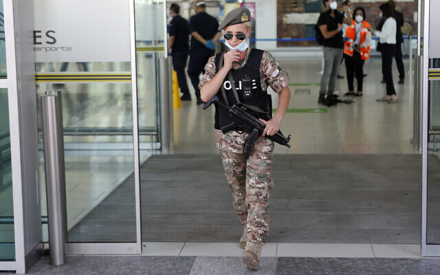 Illustrative: A female police officer adjust her mask as she guards at Cyprus' main airport in Larnaca, on June 9, 2020. (AP Photo/Petros Karadjias)
