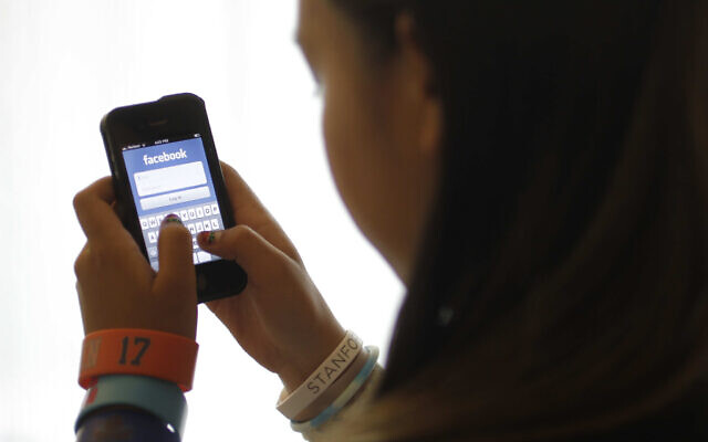 In this June 4, 2012, file photo, an unidentified 11-year-old girl logs into Facebook on her iPhone at her home in Palo Alto, Calif.  (AP Photo/Paul Sakuma, File)